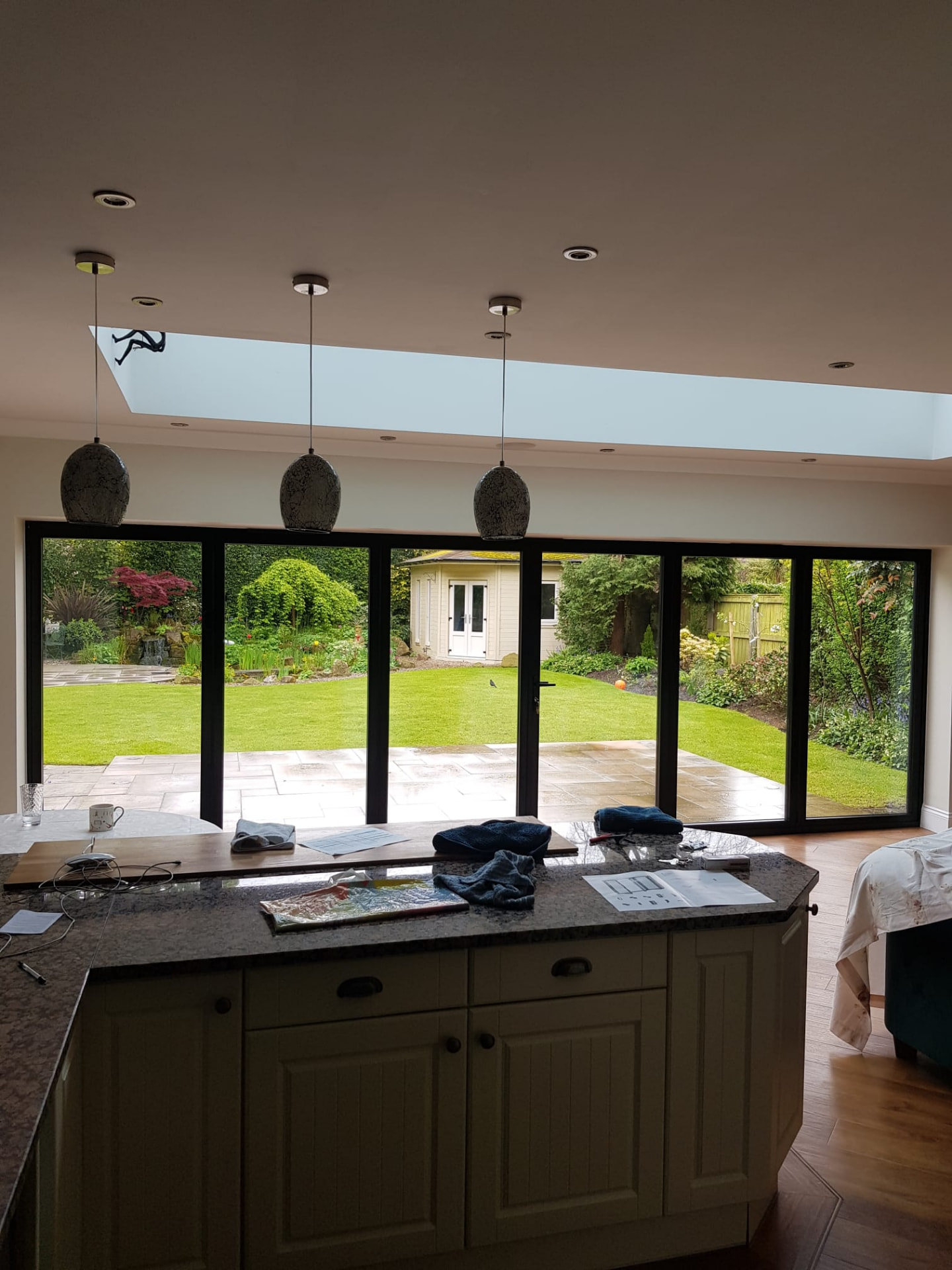 Interior kitchen view looking out through closed six-panel anthracite grey bifold doors to a lawn