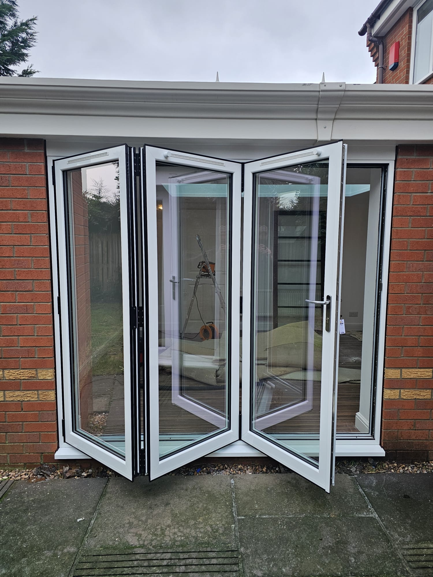 White aluminium bifold doors part folded during installation