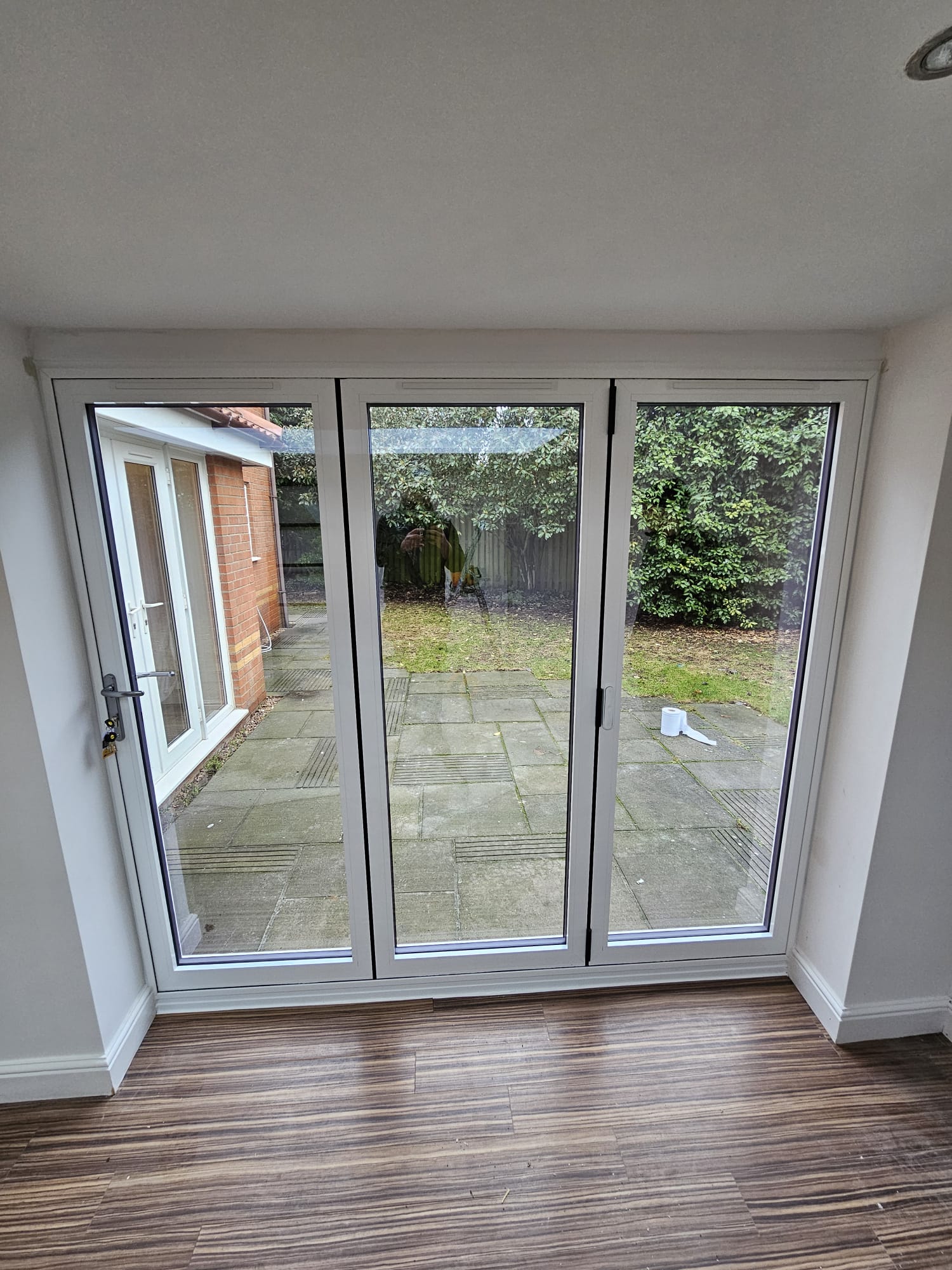 Interior view of three-panel white bifold doors looking out onto a garden
