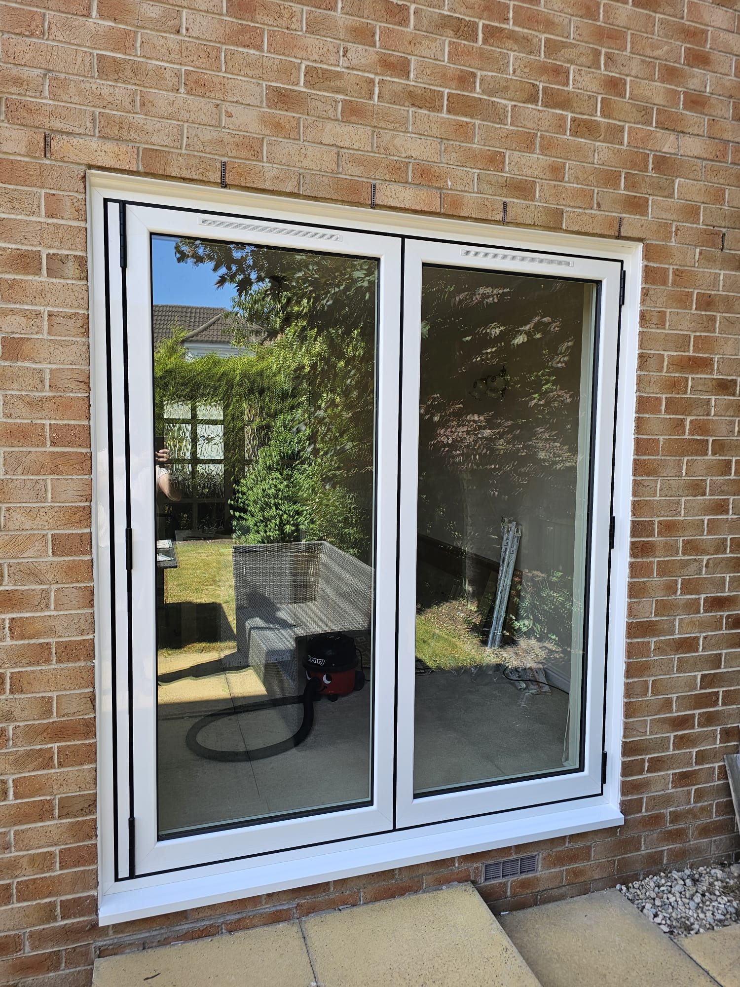 Two-panel white aluminium bifold doors closed in a brick house wall