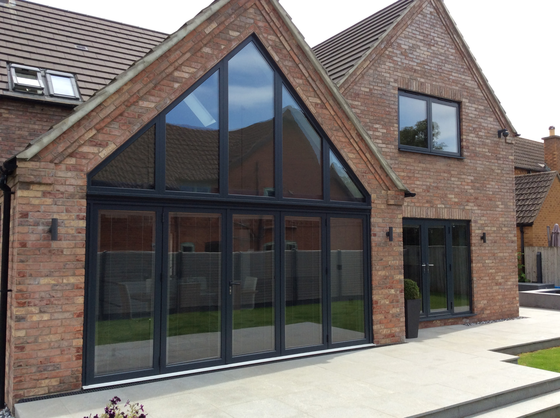 Anthracite grey bifold doors with a large matching triangular gable window above