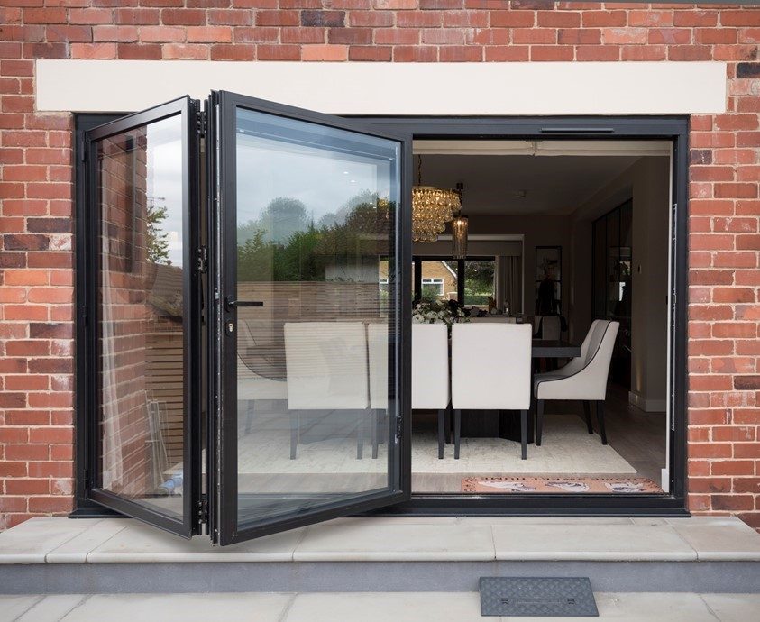 Origin aluminium bifold doors folded fully open in a wide brick opening
