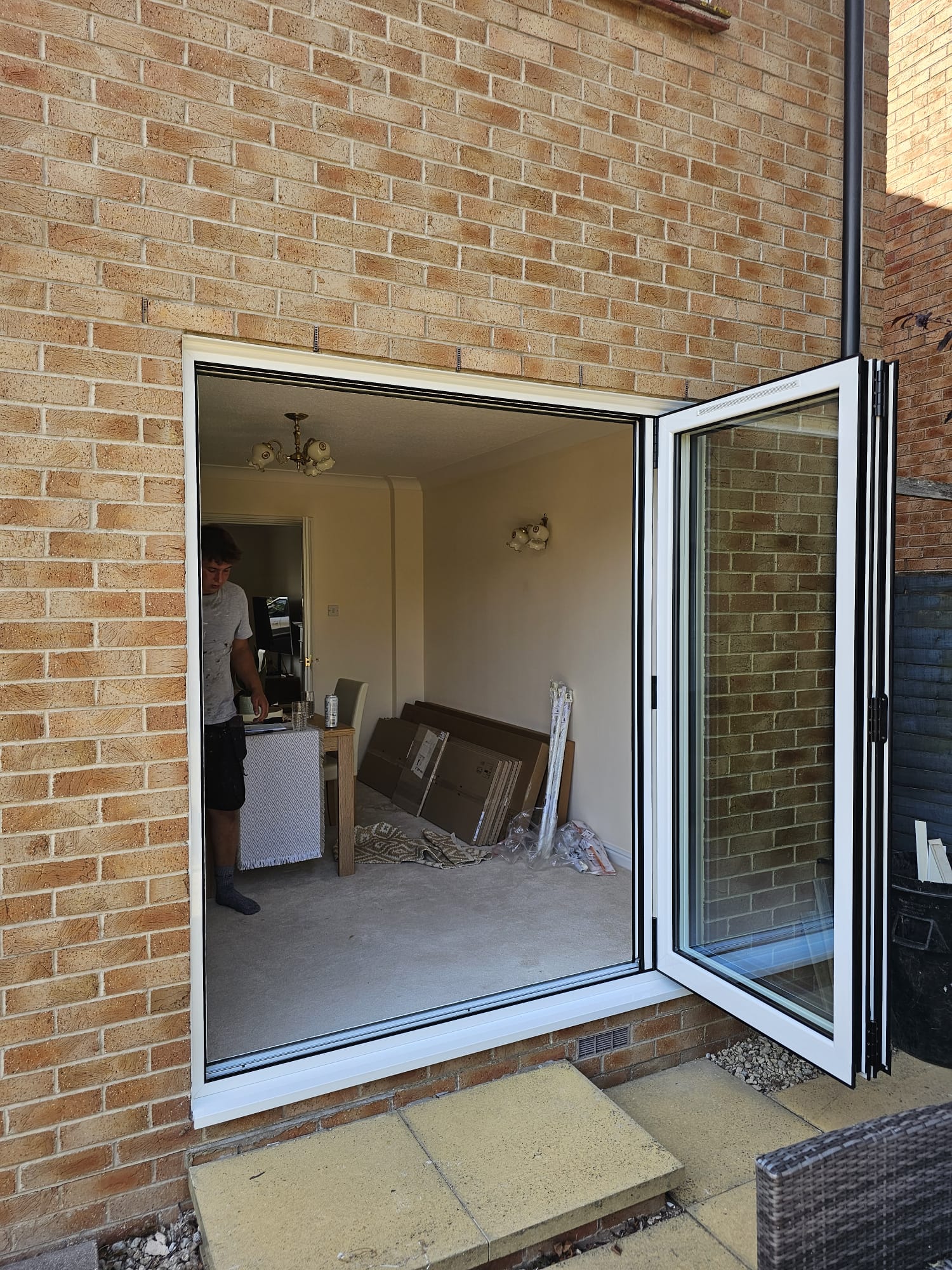 Two-panel white aluminium bifold doors folded fully open at a home