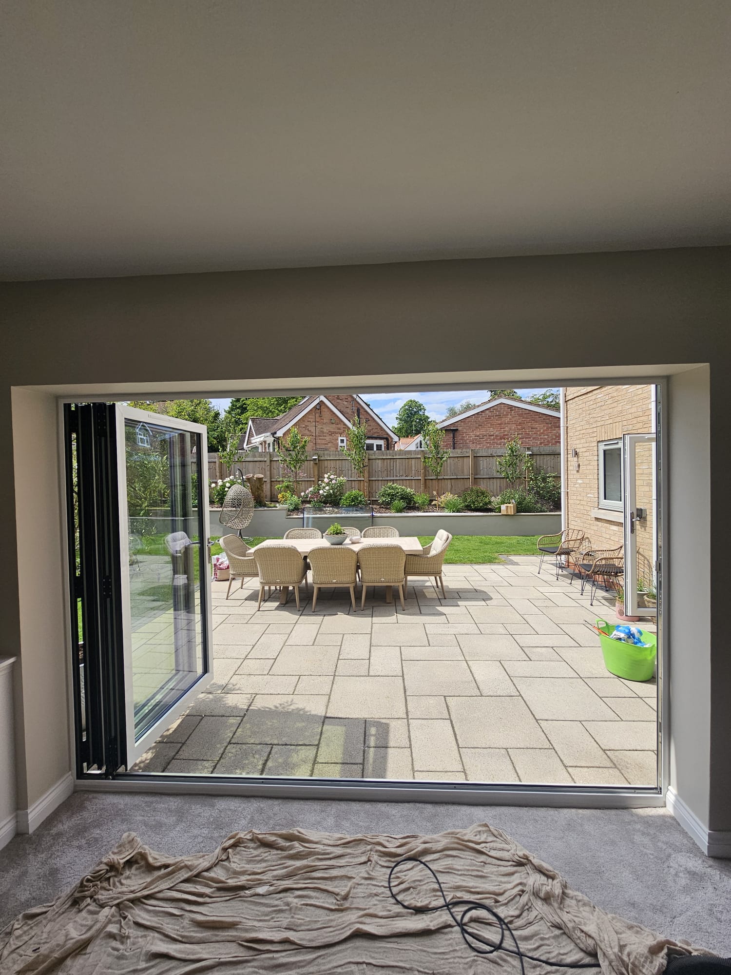 Three-panel agate grey bifold doors partly folded and stacked to one side of the opening