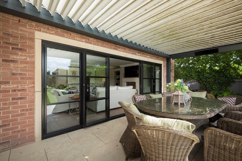 Origin aluminium bifold doors folded open onto a patio seating area