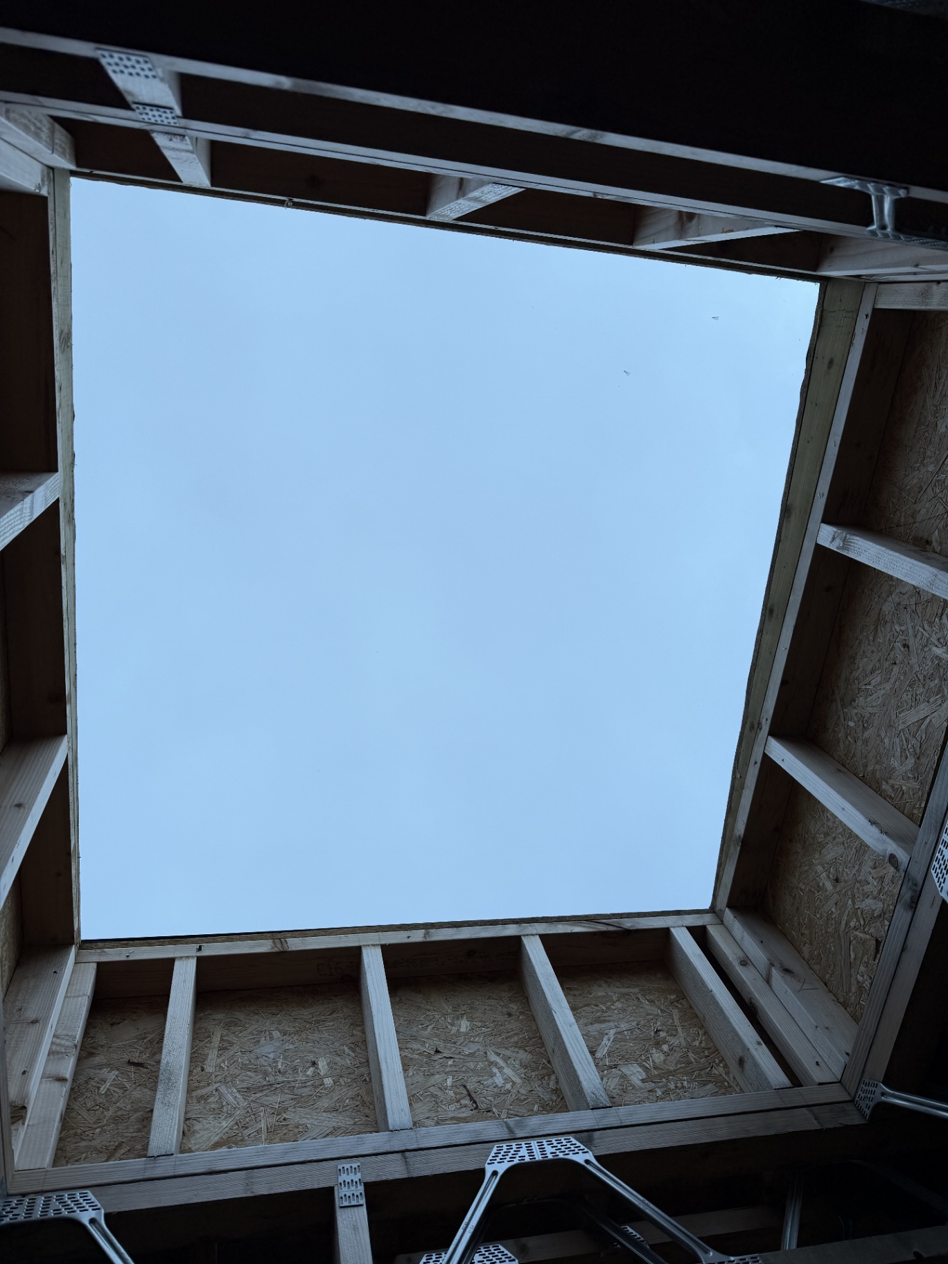 Interior view looking up through a square flat rooflight aperture