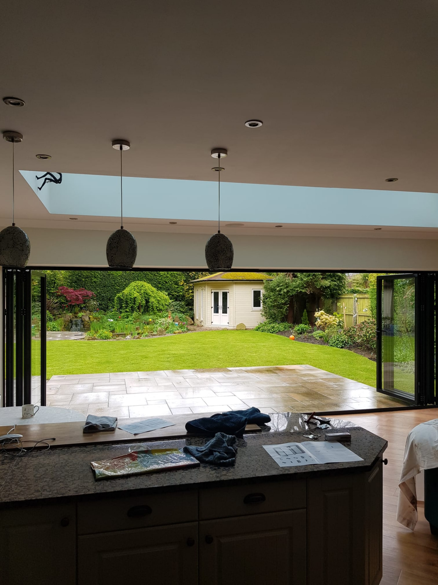 Interior kitchen view with six-panel anthracite grey bifold doors folded fully back onto the garden