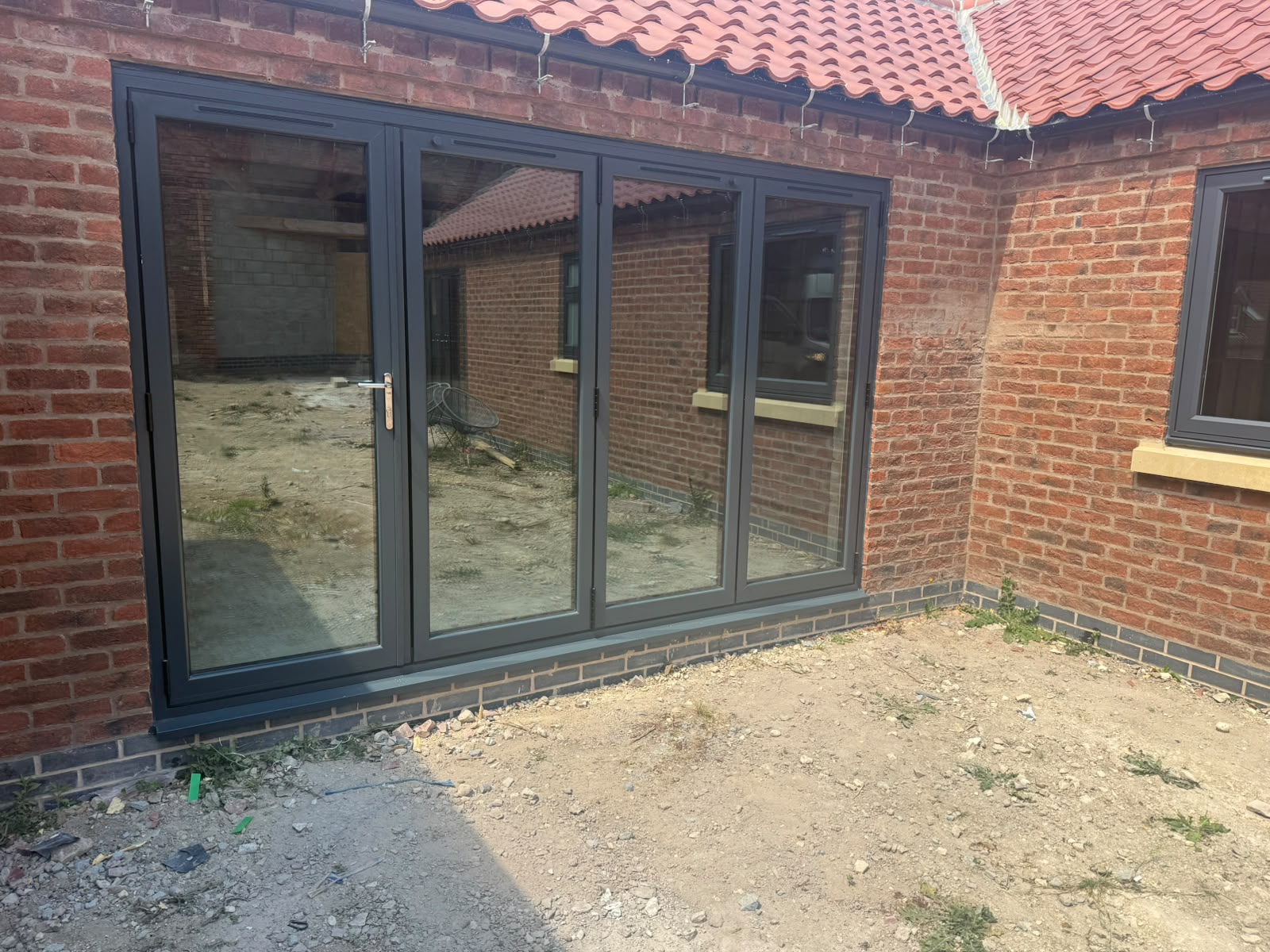 Four-panel white aluminium bifold doors installed in a new brick extension