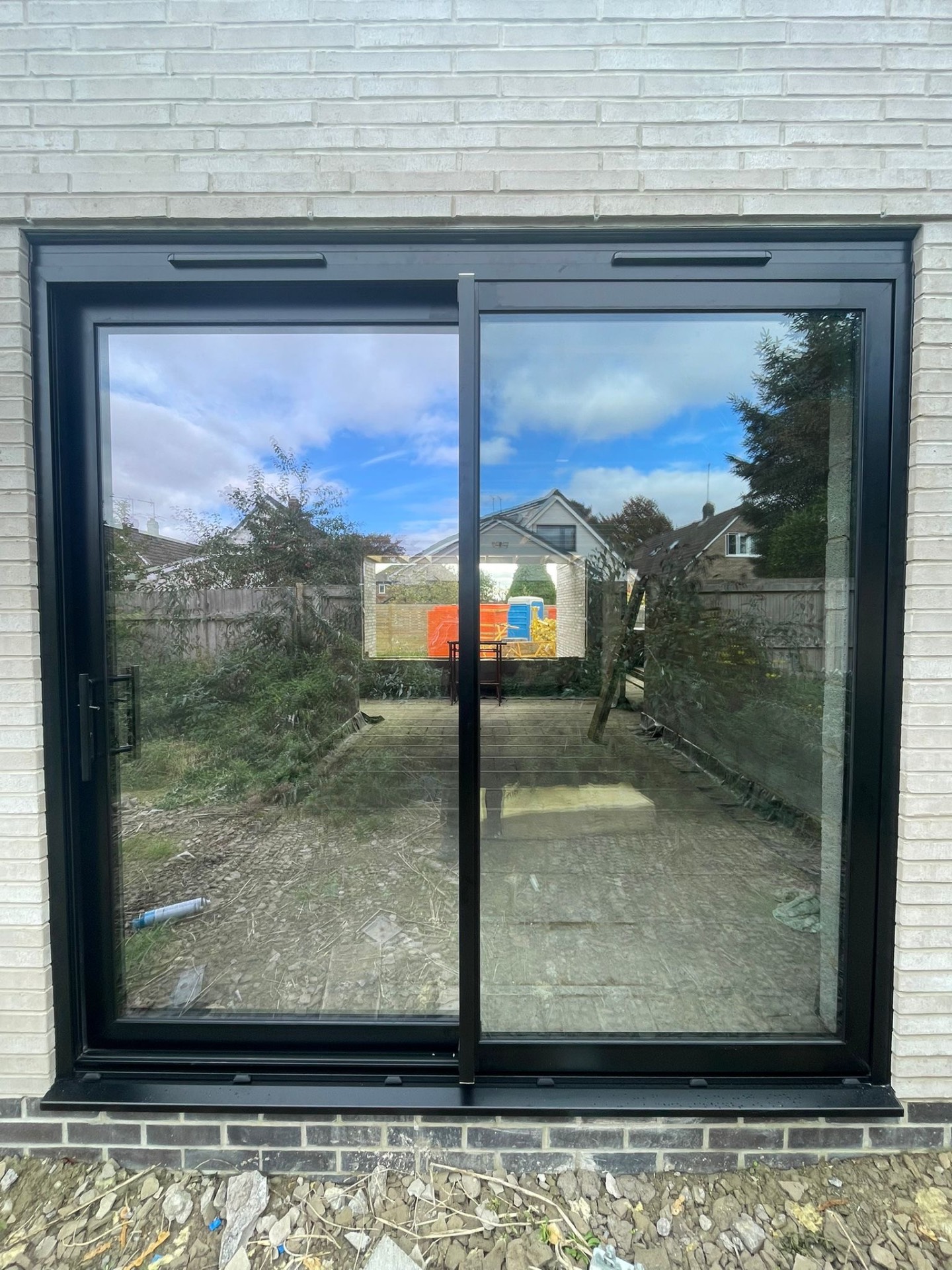 Black two-panel ALUNA aluminium sliding patio door installed in a pale brick extension